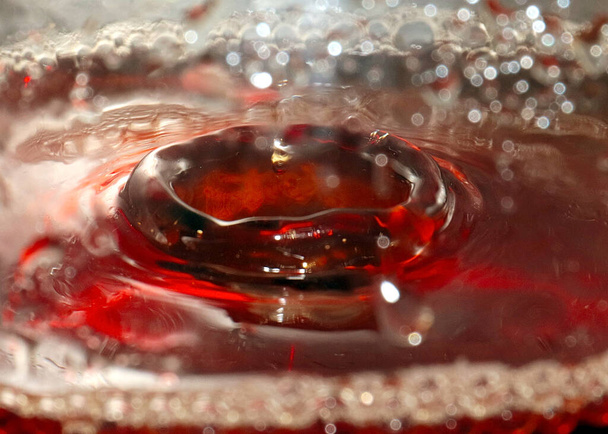a drop of strong alcohol in a glass of liquid - Fotoğraf, Görsel