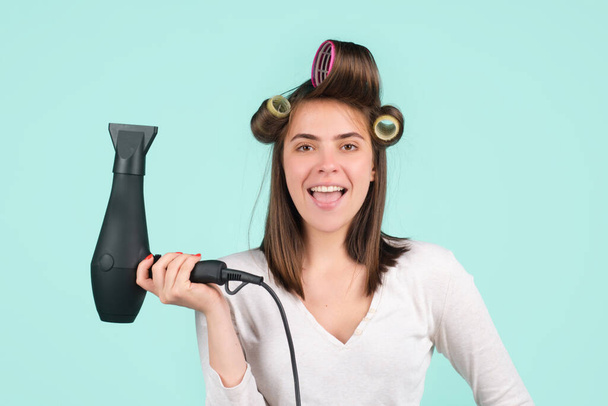 Woman with hair dryer. Funny girl with straight hair drying hair with professional hairdryer. - Фото, изображение