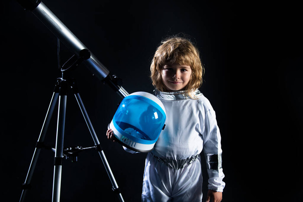 Little boy wearing an astronaut helmet costume and telescope. Cute kid in astronaut playing and dreaming of becoming a spacemen. Astronomy and astrology concept. - Foto, afbeelding