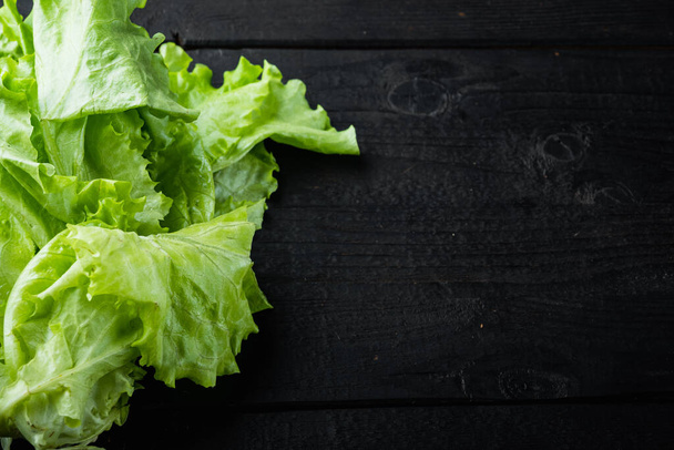Green salad lettuce fresh leaves, on black wooden table with copy space for text - Photo, image