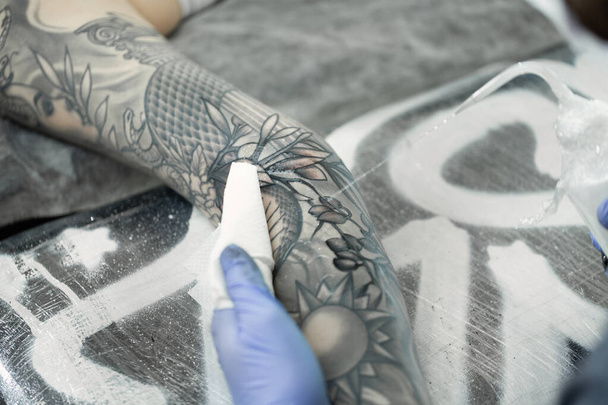Tattoo artist makes a tattoo on a young girls hand. - Фото, зображення