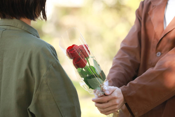 nuori aasialainen mies antaa ruusuja naiselle  - Valokuva, kuva