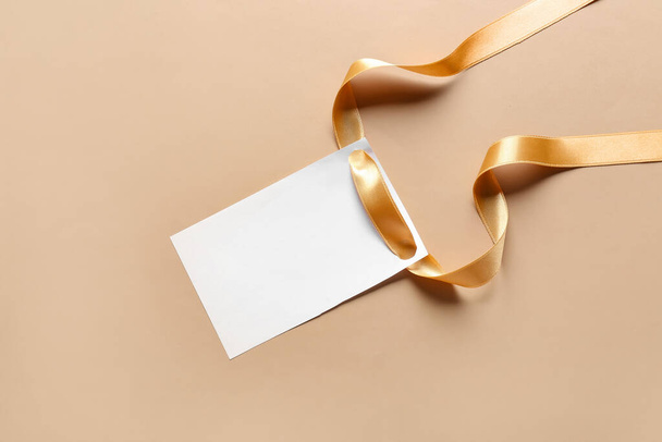 Golden ribbon with blank card on color background - Photo, Image