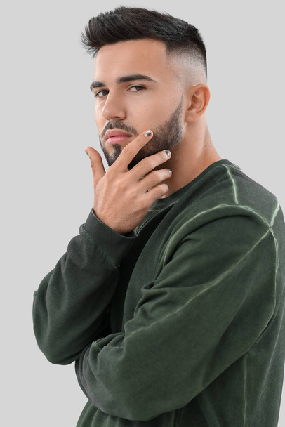 Portrait of young man with manicure on light background - Fotografie, Obrázek