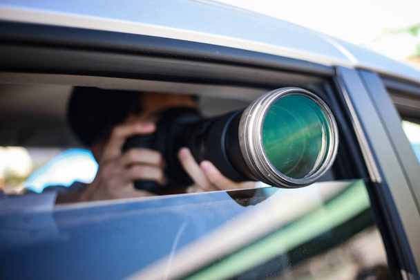enfoque selectivo de disparo de hombre joven sentado en el coche con una cámara - Foto, Imagen