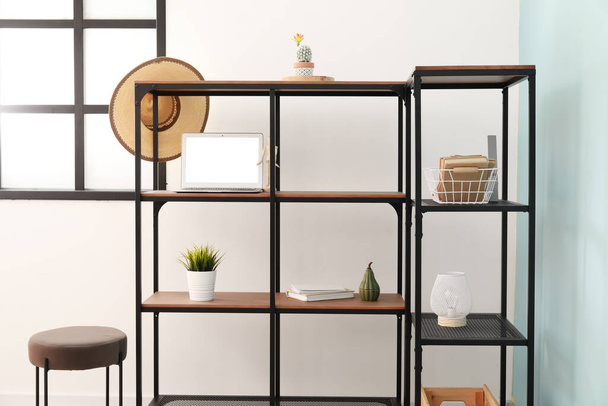 Modern shelf unit with decor and laptop in light room - Foto, Imagem