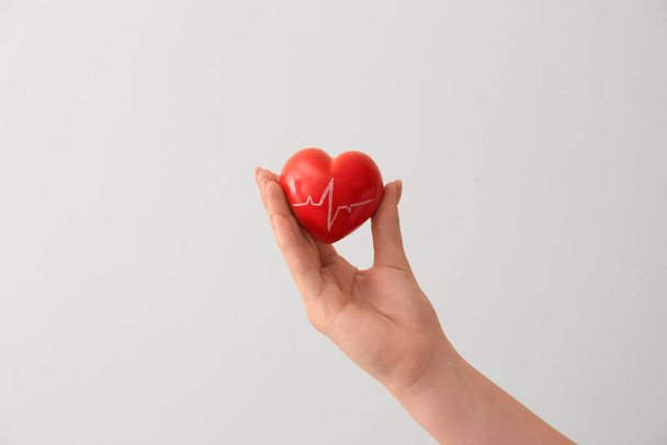 Женщина держит красное сердце с кардиограммой на цветном фоне, крупным планом. Концепция пожертвований - Фото, изображение