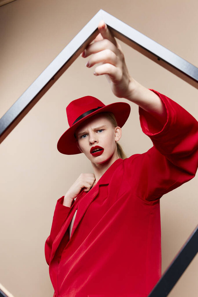 marco de mujer glamorosa en la mano en sombrero rojo y chaqueta de fondo aislado - Foto, Imagen