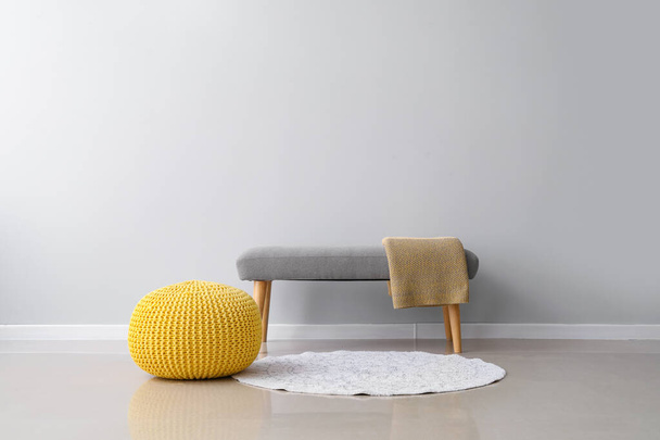 Comfortable pouf and bench with plaid near light wall - Фото, изображение