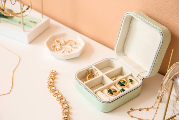 Opened box with stylish jewelry on white table near color wall - Valokuva, kuva