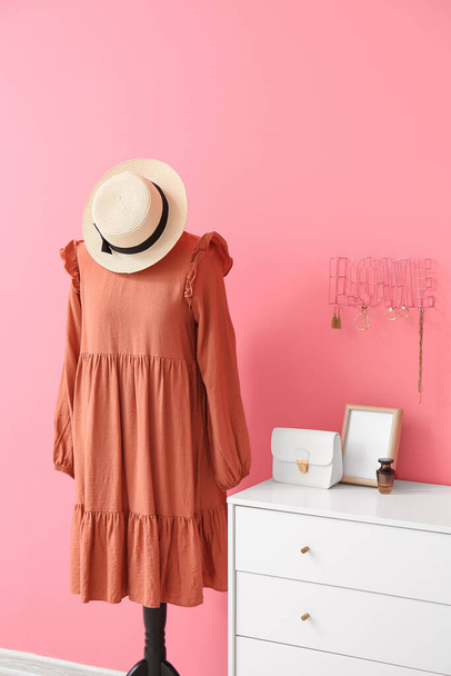 Etalagepop met jurk en ladekast met stijlvolle accessoires in de buurt van kleur muur - Foto, afbeelding