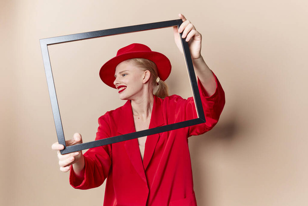 portret van een vrouw rode lippen mode jasje frame beige achtergrond - Foto, afbeelding