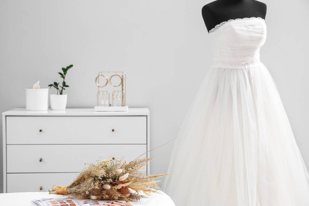 Ramo de flores y maniquí con vestido de novia en sala de luz - Foto, Imagen