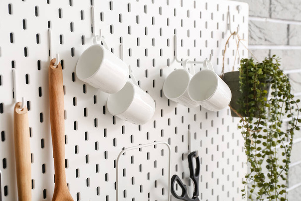 Pegboard com copos e utensílios de cozinha na parede - Foto, Imagem