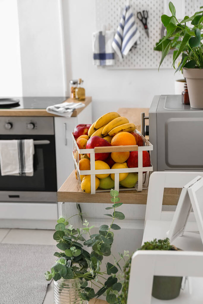 Кошик зі смачними фруктами і кімнатними рослинами на столі на кухні
 - Фото, зображення