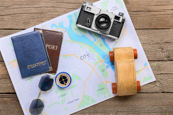 Appareil photo, passeports, voiture en bois, lunettes de soleil et carte sur fond en bois - Photo, image
