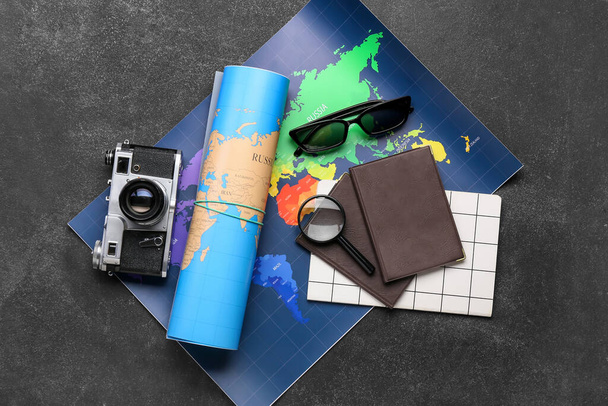 Fényképezőgép, napszemüveg, útlevelek és térképek sötét háttérrel - Fotó, kép