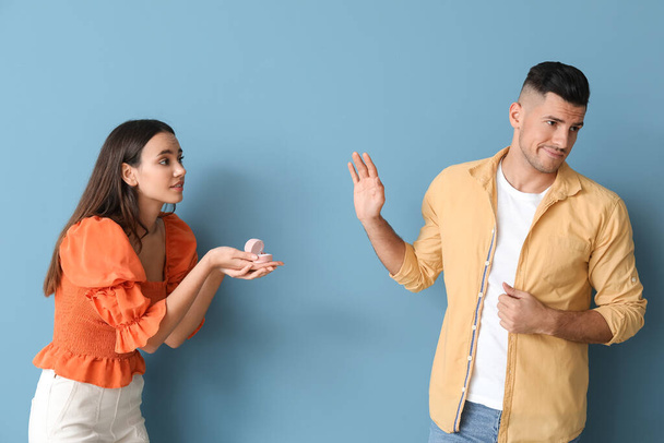Young man rejecting marriage proposal on color background - Φωτογραφία, εικόνα