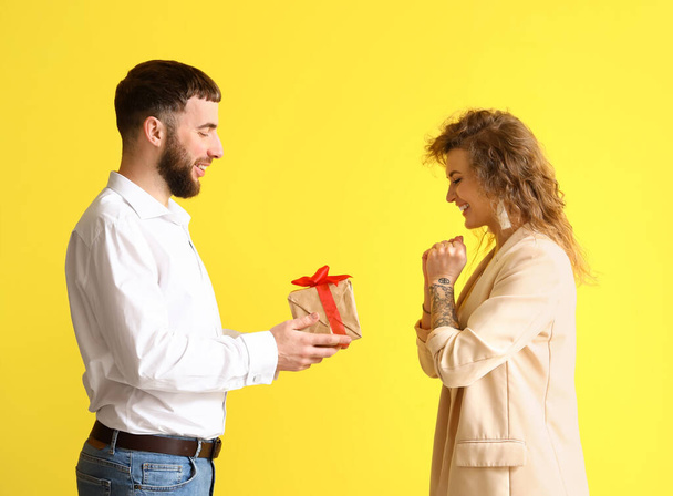Happy man greeting his girlfriend for Valentine's Day on color background - Photo, Image