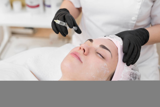Woman face cosmetology treatment. Biorevitalization skin therapy. Injecting in medical salon. The procedure of biorevitalization in the area of eyes with a preparation with hyaluronic acid - Foto, Bild