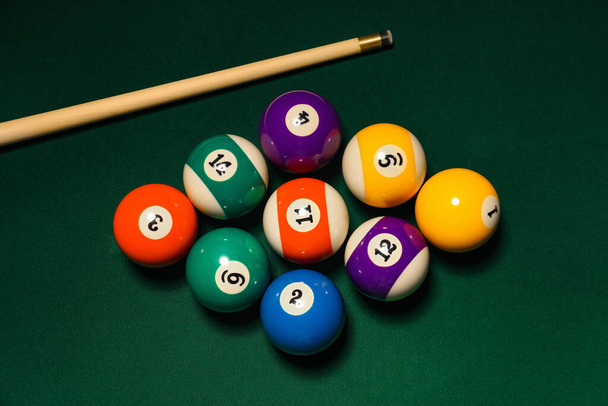 Diverse palle da biliardo con stecca sul tavolo verde - Foto, immagini