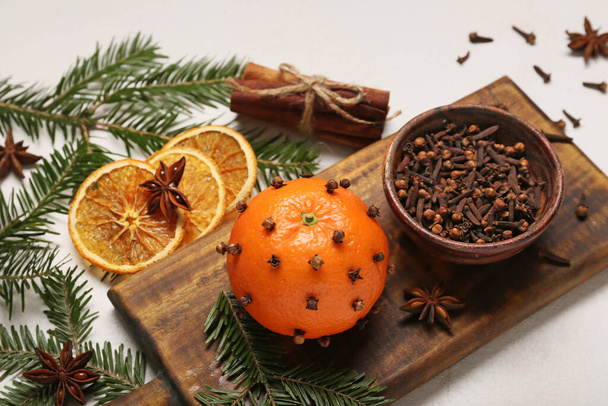 Handgemaakte kerstversiering gemaakt van mandarijn met kruidnagel en sparren takken op lichte achtergrond, close-up - Foto, afbeelding