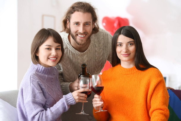 Muž a dvě krásné ženy pijí víno doma. Koncepce polyamorie - Fotografie, Obrázek