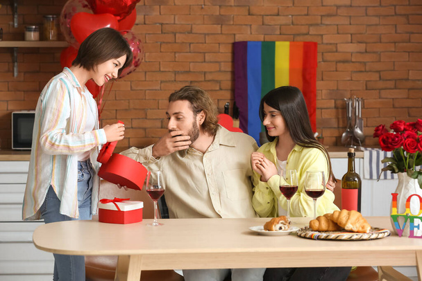 Mies ja kaksi kaunista naista juhlivat ystävänpäivää kotona. Polyamorinen käsite - Valokuva, kuva