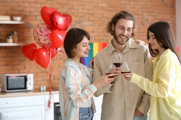 Hombre y dos mujeres hermosas bebiendo vino en casa. Concepto de poliamory - Foto, imagen
