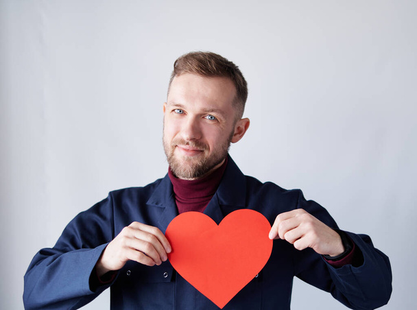 Bearded happy electrician or engineer with red paper heart - Foto, imagen