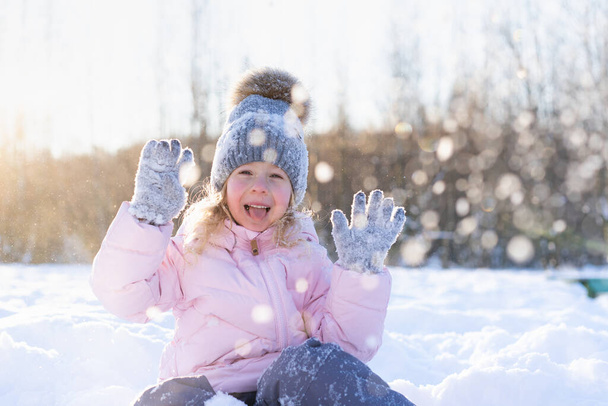 little girl rides down the slide on the ice, cheerful child, emotions from winter fun - Photo, Image