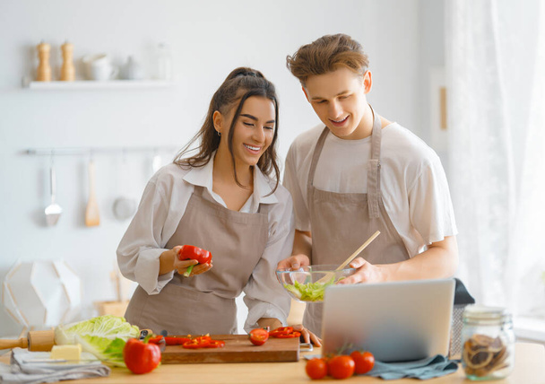 Healthy food at home. Happy loving couple is preparing the proper meal in the kitchen. - Фото, изображение