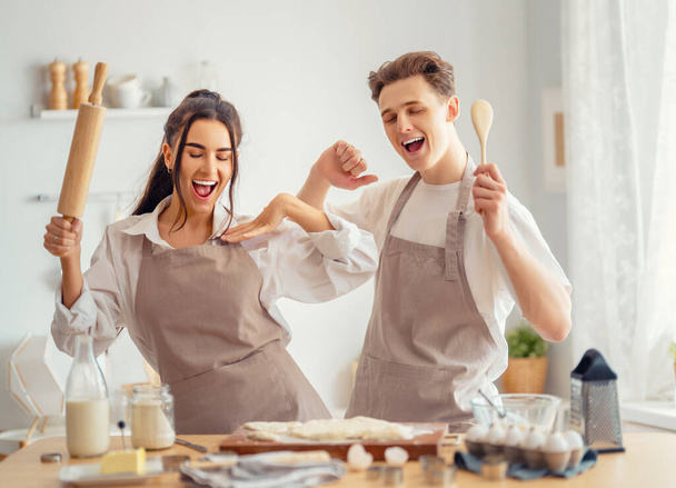 Feliz pareja amorosa está preparando la pastelería en la cocina. - Foto, Imagen