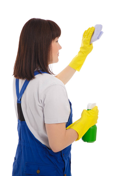 πίσω όψη της επαγγελματικής καθαρίστρια σε μπλε στολή καθαρισμού κάτι με πανί και απορρυπαντικό σπρέι απομονώνονται σε λευκό φόντο - Φωτογραφία, εικόνα