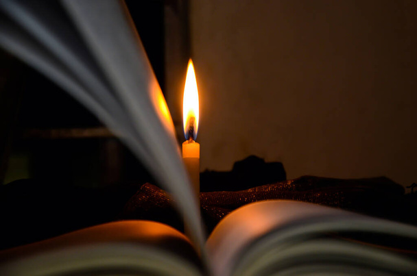 Молниеносная свеча в книге переворачивается. Свет свечи и открытая книга - Фото, изображение