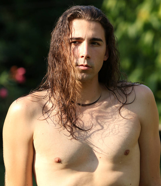Attractive guy with very long hair is posing in the wild. Modeling and Fashion Concept. - Foto, Bild