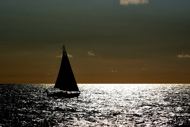 Purjevene purjehtii merellä tuulisena ja aurinkoisena päivänä, ennen auringonlaskua - Valokuva, kuva