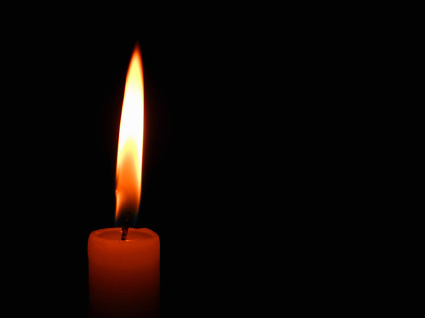 Una sola vela encendida con bastante llama. Llama de vela ardiente dramática sobre un fondo negro con espacio para copiar - Foto, imagen