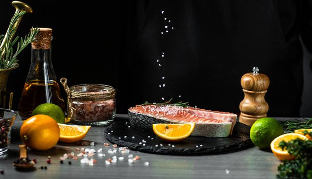Cocine prepara salmón filete pescado, rociando sal marina en un movimiento de congelación o negro. banner, lugar de la receta del menú para el texto. - Foto, Imagen