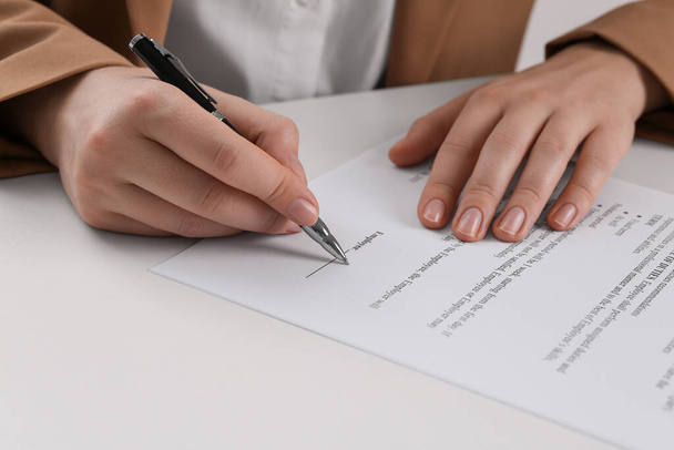 Businesswoman signing contract at white table, closeup of hands - Foto, Imagem