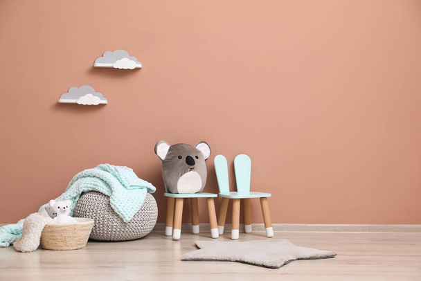 Child's toys, pouf and chairs near pink wall indoors. Interior design - Foto, Imagen