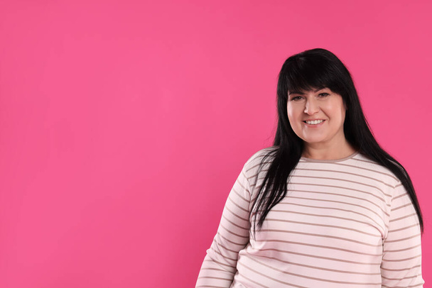 Beautiful overweight mature woman with charming smile on pink background. Space for text - Fotó, kép