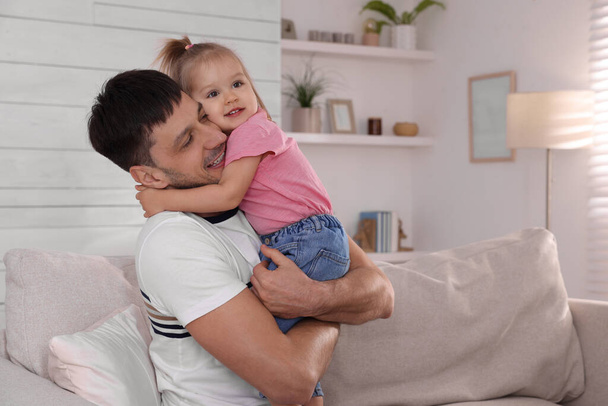 Father with his cute little daughter on sofa at home - Φωτογραφία, εικόνα