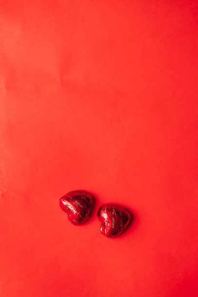 Valentine's Day. On red table lies two candies in form of heart - Φωτογραφία, εικόνα