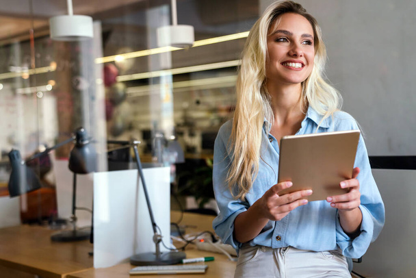 Portrait of an attractive young businesswoman smiling working on digital tablet in office. Business work people concept - Photo, image