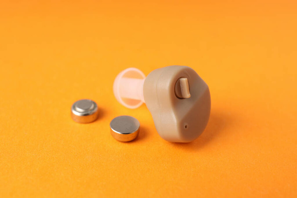 Concepto de cuidado de la salud con audífono sobre fondo naranja - Foto, imagen
