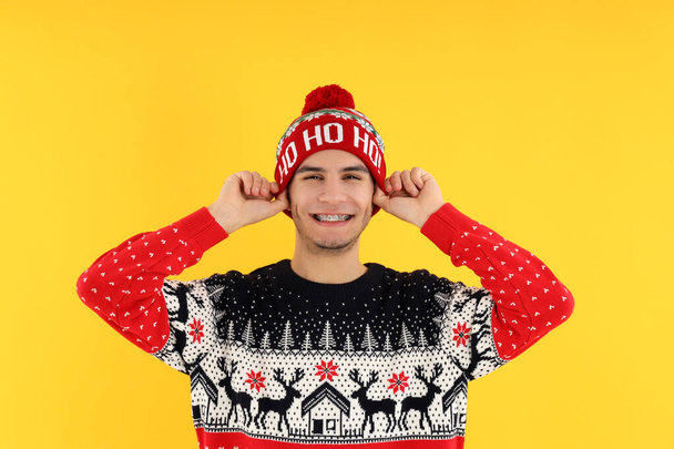 Attractive guy in Christmas sweater on yellow background - Fotó, kép