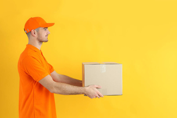 Delivery guy hold box on yellow background - Photo, Image