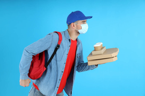 Delivery man with food on blue background - Photo, Image