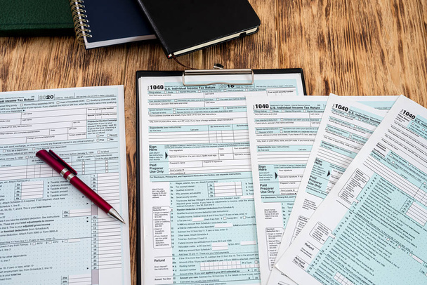 lindos cadernos formulários fiscais líquidos EUA 1040 para preenchimento por cidadãos e carrinho de caneta vermelha na mesa de madeira. Conceito de documentação - Foto, Imagem